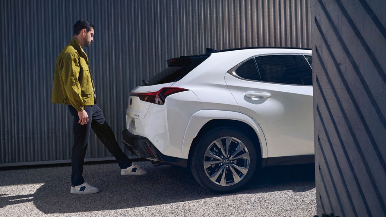 A person stood next to a white Lexus UX